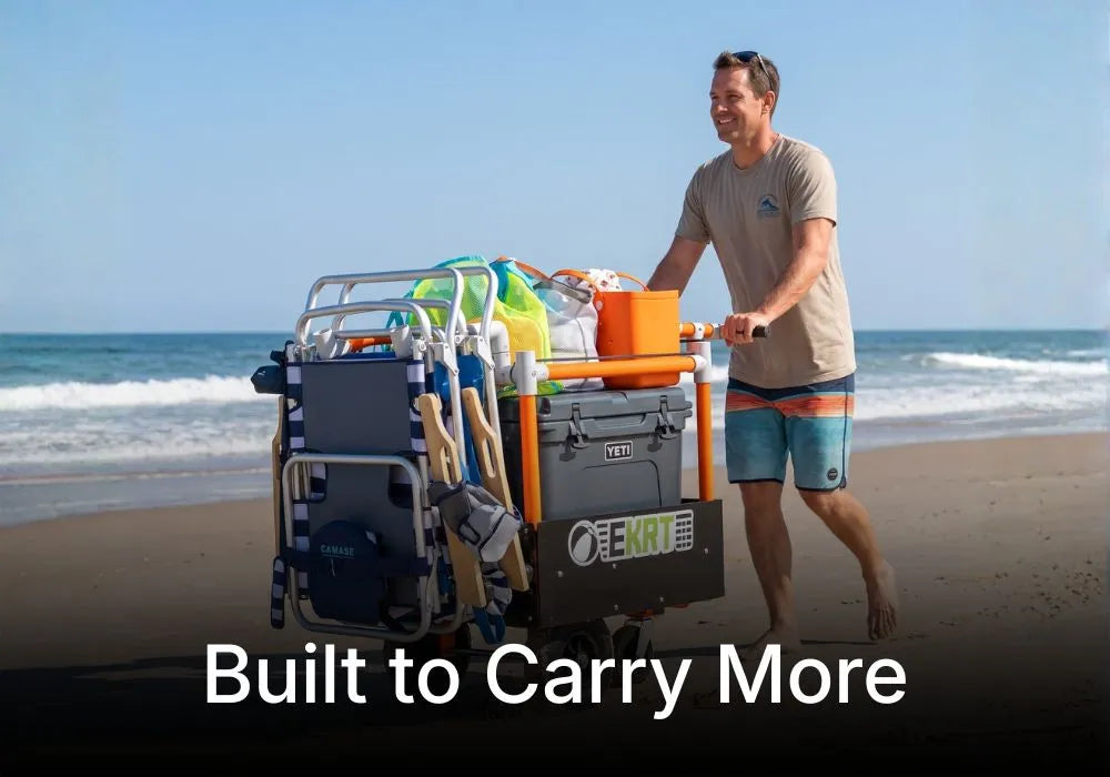 A man on a beach pushes an electric beach cart effortlessly with beach gear, including a folding chair, towels, and an orange bucket. 