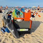 Orange e-KRT electric beach cart loaded with a cooler, chairs, and beach bags on a boardwalk