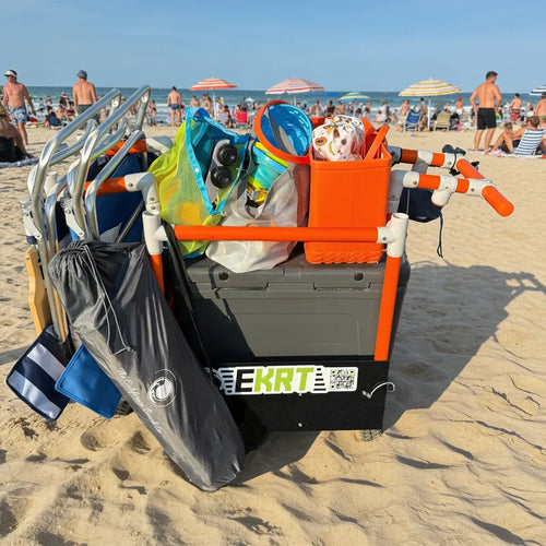 Orange e-KRT electric beach cart loaded with a cooler, chairs, and beach bags on a boardwalk