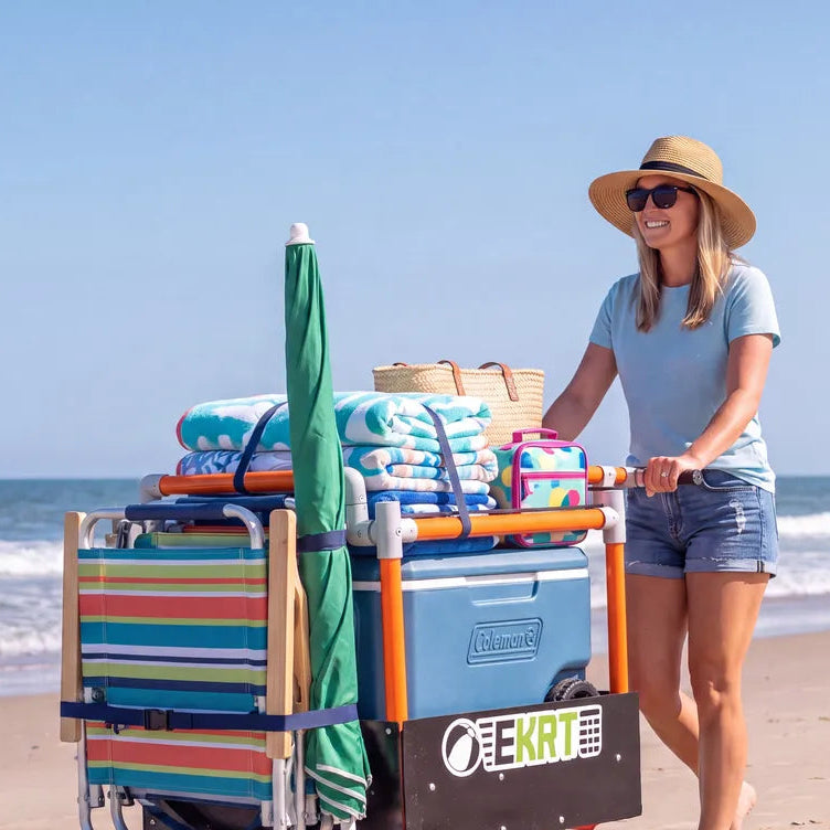 Person standing beside a loaded e-KRT electric beach cart on a beach dune path
